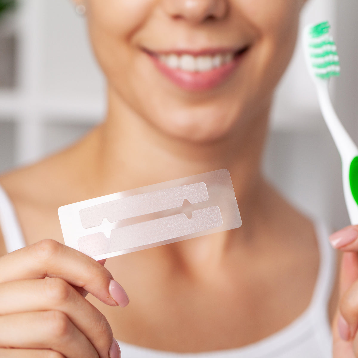 Usmievajúca sa žena držiaca bieliace pásiky na zuby